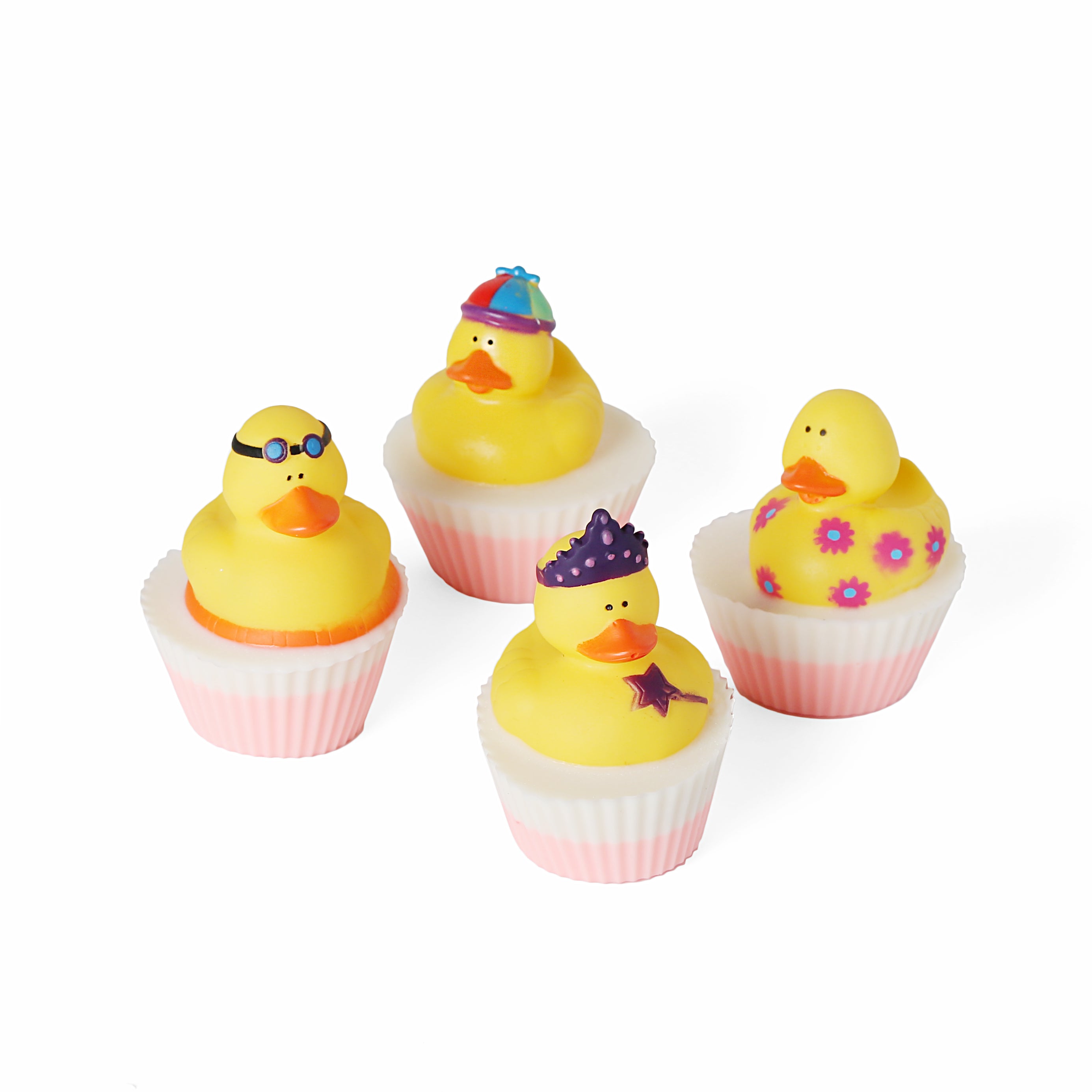 Collection of four rubber Duckie soaps. Round shaped with light pink and white liners. Topped with different variations of yellow ducks. One has a crown and magic wand, one has flowers, one has goggles, and one has colorful hat.
